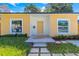 Close up of yellow home showcasing its welcoming front door and well-kept lawn at 1432 19Th S St, St Petersburg, FL 33712