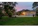 Expansive backyard with a well-manicured lawn, lush trees, swimming pool, and comfortable outdoor seating at twilight at 14344 83Rd Pl, Seminole, FL 33776
