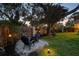 Cozy backyard with a fire pit surrounded by Adirondack chairs, complemented by decorative lighting and greenery at 14344 83Rd Pl, Seminole, FL 33776