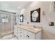 Bright bathroom featuring a double vanity, framed mirrors, a tiled shower, and textured walls at 14344 83Rd Pl, Seminole, FL 33776