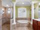 Primary bathroom features a soaking tub, walk-in shower, linen closet and elegant decorative columns at 16529 Ivy Lake Dr, Odessa, FL 33556