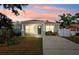 Charming single-story home features a well-manicured lawn and a concrete driveway at sunset at 2410 26Th S St, St Petersburg, FL 33712