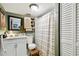 Inviting bathroom with a neutral palette, featuring a shower with a curtain, a wooden cabinet, white sink, and storage space at 2708 N Mitchell Ave, Tampa, FL 33602