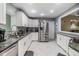 Modern kitchen featuring white cabinetry, granite countertops, stainless steel appliances, and herringbone tile floors at 2779 Diane Ter, Clearwater, FL 33759