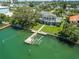 A beautiful aerial view of a luxurious waterfront property with a boat dock, lush lawn, and clear water at 3 Paradise Ln, Treasure Island, FL 33706