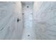 Walk-in shower featuring marble-style tile walls, a tile floor, and built-in shelving at 3329 Roxbury Dr, Holiday, FL 34691