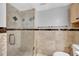Well-lit bathroom shower with a built-in shower caddy and upscale beige stone tile at 400 Island Way # 201, Clearwater Beach, FL 33767