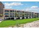 A beachfront condo building with balconies and lush landscaping next to a green lawn at 7564 Bayshore Dr # 306, Treasure Island, FL 33706