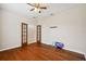 A spacious empty room with hardwood flooring, ceiling fan, and adjacent room, allowing flexible layout options at 8437 White Poplar Dr, Riverview, FL 33578