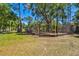 Community playground featuring a swing set, enclosed by a chain-link fence, among lush trees and grassy area at 8437 White Poplar Dr, Riverview, FL 33578