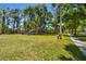 Community playground featuring a swing set and slide, enclosed by a chain-link fence, set amid lush trees and lawn at 8437 White Poplar Dr, Riverview, FL 33578