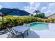 Backyard features a pool, poolside table and chairs beneath an umbrella, and lush tropical landscaping at 9715 Pleasant Run Way, Tampa, FL 33647
