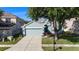 View of a light blue single-story home with a driveway, attached garage, and landscaped yard at 9954 N Jasmine Brook E Cir, Land O Lakes, FL 34638