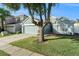 Light blue single-story home with a driveway, attached garage, landscaped yard, and large tree at 9954 N Jasmine Brook E Cir, Land O Lakes, FL 34638