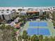 A scenic aerial view showcases tennis courts, landscaping, and complex near beach at 7564 Bayshore Dr # 306, Treasure Island, FL 33706