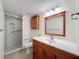 Well-lit bathroom featuring a tile shower, toilet, vanity, mirror, and wood cabinets at 110 W Cypress Ct, Oldsmar, FL 34677