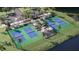 Overhead view of pickleball courts with green fencing, surrounded by landscaping, parking, and a water feature at 13130 Empress Jewel Trl, Parrish, FL 34219