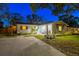 Charming home exterior with stucco, a well-manicured lawn, mature trees and a quaint porch seating area at 1543 Gentry St, Clearwater, FL 33755