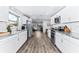Modern white kitchen with stainless steel appliances, granite countertops, and wood-look vinyl floors at 1543 Gentry St, Clearwater, FL 33755