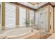 Soaking tub and shower behind glass doors in well appointed bathroom with window louvers at 1655 Eagles Reach, Tarpon Springs, FL 34688