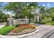 Community entrance featuring stone signage surrounded by vibrant landscaping and mature trees at 1655 Eagles Reach, Tarpon Springs, FL 34688