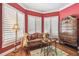 Sitting area by window with louvers and a cozy settee. Hardwood floors and red painted walls at 1655 Eagles Reach, Tarpon Springs, FL 34688