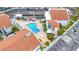 Aerial view of a community pool surrounded by sun loungers, lush landscaping, and charming condo buildings at 253 Rex Pl # B, Madeira Beach, FL 33708