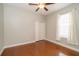 Cozy bedroom with hardwood floors, ceiling fan, standard closet with bi-fold doors, and sheer white curtains at 27130 Firebush Dr, Wesley Chapel, FL 33544