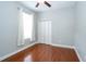 Neutral bedroom featuring hardwood floors, standard closet, ceiling fan, and a window with white sheer curtains at 27130 Firebush Dr, Wesley Chapel, FL 33544