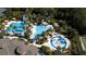 Aerial view of the community pool and splashpad surrounded by mature palm trees and shade structures at 27130 Firebush Dr, Wesley Chapel, FL 33544