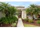 Inviting home entrance with lush tropical landscaping, mature palm trees, and a welcoming walkway at 27130 Firebush Dr, Wesley Chapel, FL 33544