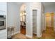Hallway featuring travertine floors, arched doorway, and a pantry with wire shelving at 27130 Firebush Dr, Wesley Chapel, FL 33544