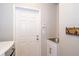 Practical laundry room featuring a utility sink, storage cabinet, coat hooks and exterior access door at 27130 Firebush Dr, Wesley Chapel, FL 33544