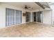 Covered patio area with travertine flooring, ceiling fan, and sliding glass doors with sheer curtains at 27130 Firebush Dr, Wesley Chapel, FL 33544