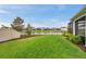 Spacious backyard with lush lawn, rod iron fence, view of a pond, and screened-in patio at 28683 Lucero Ln, Wesley Chapel, FL 33543