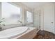 Bright bathroom with a luxurious soaking tub beneath a window and a separate glass-enclosed shower at 28683 Lucero Ln, Wesley Chapel, FL 33543