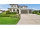 Charming two-story home featuring a three-car garage, arched entryway, and meticulously landscaped front yard at 28683 Lucero Ln, Wesley Chapel, FL 33543
