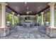 Outdoor kitchen and entertaining space with multiple ceiling fans, stone columns, and ample seating at 28683 Lucero Ln, Wesley Chapel, FL 33543