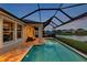 Screened pool with blue water near lake, and covered patio with fan and furniture at 28683 Lucero Ln, Wesley Chapel, FL 33543