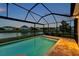 Screened pool with blue water near lake, and houses at back at 28683 Lucero Ln, Wesley Chapel, FL 33543