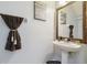 Powder room featuring a pedestal sink, decorative mirror and dark brown hand towel with tassels at 30130 Mossbank Dr, Wesley Chapel, FL 33543