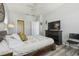 Bedroom with wood-look flooring, queen bed, dresser with TV, and white curtains at 30130 Mossbank Dr, Wesley Chapel, FL 33543