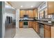 Open concept kitchen with stainless steel appliances, wooden cabinets, tile backsplash, and a stainless steel refrigerator at 30130 Mossbank Dr, Wesley Chapel, FL 33543