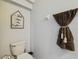 Toilet in a powder room with neutral paint, decorative wall art and a dark brown towel with tassels at 30130 Mossbank Dr, Wesley Chapel, FL 33543