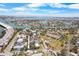 Aerial view of property with mature trees, landscaping, park, tennis court and ocean in the distance at 3214 E Maritana Dr, St Pete Beach, FL 33706