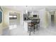 Open kitchen and living area with white cabinets, stainless appliances, tile flooring, and barstools at 3214 E Maritana Dr, St Pete Beach, FL 33706