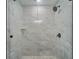 Modern shower boasts large, stylish tiles, glass door, rainfall shower head, and built-in shelving at 3214 E Maritana Dr, St Pete Beach, FL 33706