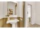 Elegant half bathroom featuring a pedestal sink, large mirror, and a view into the house's living room at 413 W Park Ave # 1, Tampa, FL 33602