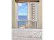 Bright bedroom view showcasing ocean and neighboring building through a large window at 450 S Gulfview Blvd # 802, Clearwater Beach, FL 33767