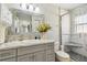 Bathroom features a shower with white marble-look tiles and gray vanity with countertop decor and flowers at 4606 Copper Ln, Plant City, FL 33566